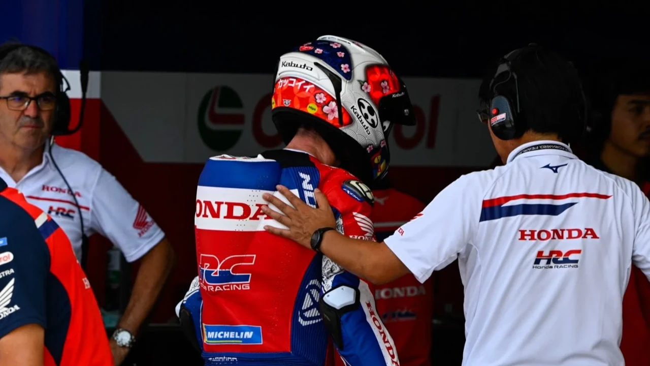 Aleix Espargaró in Honda HRC racing leathers receives assistance from a Honda team member in the garage during the 2026 Indonesian MotoGP weekend at Mandalika.